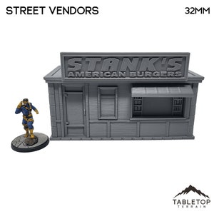 Puede incluir: Un modelo gris de 32 mm a escala de un puesto de vendedor ambulante con un letrero que dice "Stank's American Burgers".