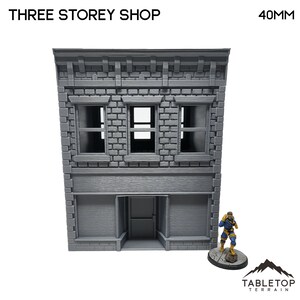 Puede incluir: Un edificio de tienda gris de tres pisos con una fachada, ventanas y una fachada de ladrillo. El edificio tiene 40 mm de altura.  "THREE STOREY SHOP" y "40MM" están impresos en la imagen.