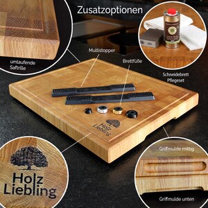 May include: A square wooden chopping board with a juice groove, featuring a branded tree logo and the text Holz Liebling. Accessories include two black multistoppers, four circular feet, and a maintenance kit with oil, sandpaper, and a cloth.