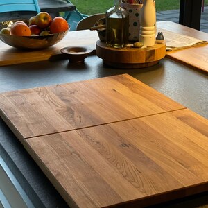 K&ouml;nnte beinhalten: Zwei Holzschneidebretter, eines auf dem anderen, liegen auf einer grauen Arbeitsplatte. Die Bretter sind aus hellem braunem Holz mit nat&uuml;rlicher Maserung. Die Bretter sind rechteckig und haben abgerundete Kanten.