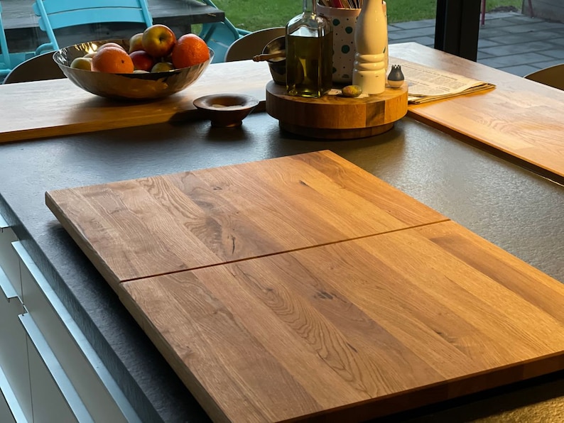 K&ouml;nnte beinhalten: Zwei Holzschneidebretter, eines auf dem anderen, liegen auf einer grauen Arbeitsplatte. Die Bretter sind aus hellem braunem Holz mit nat&uuml;rlicher Maserung. Die Bretter sind rechteckig und haben abgerundete Kanten.