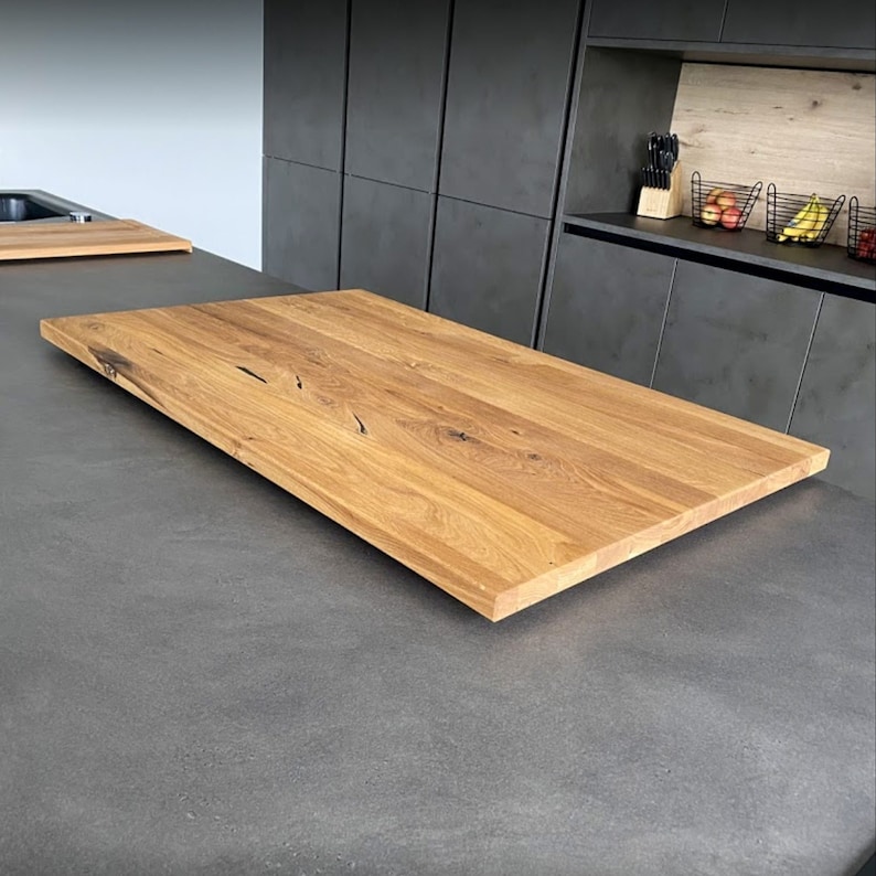 May include: A close-up of a light brown wooden countertop with a natural wood grain pattern. The countertop is made of solid wood and has a smooth, polished finish.