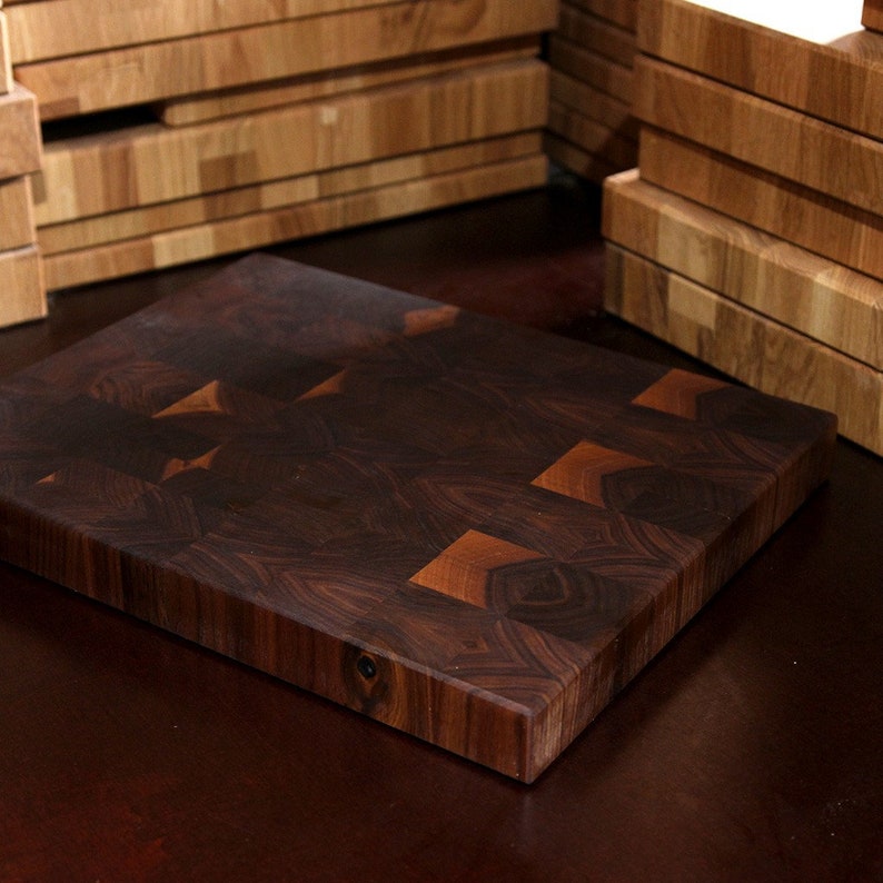May include: A rectangular end-grain chopping board constructed from dark brown walnut wood blocks. The surface features a visible grid pattern of alternating wood grain directions, showcasing natural variations in colour from deep espresso to lighter tan.