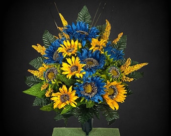 This cemetery cone has grave flowers including yellow and blue sunflowers and spike filler. It's a funeral or memorial decoration.