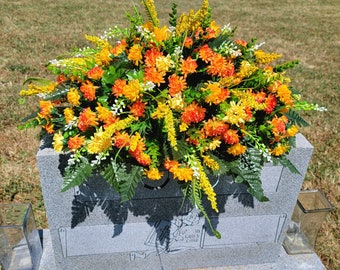 This Large Headstone Saddle has grave flowers including Orange Mix Mini-Mums. It is a funeral or memorial decoration.