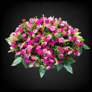 This Headstone Saddle has grave flowers including Beauty Pink Mini Mums. It is a perfect funeral or cemetery decoration.