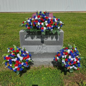 This is a Patriotic Headstone Saddle with cemetery cones; it has veteran grave flowers including Red, White, and Blue Mini Mums.