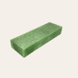 May include: A green rectangular block of floral foam, used for arranging flowers.