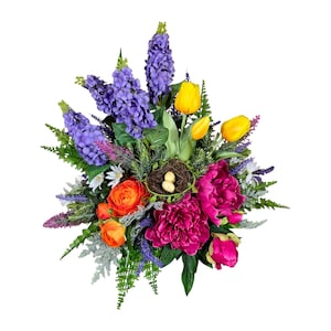 May include: A vibrant floral arrangement featuring purple hyacinths, yellow tulips, orange ranunculus, and deep pink peonies. A small nest with two eggs is nestled among the flowers, creating a spring-like display.
