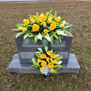 This Memorial Decoration includes 1 Headstone Saddle & 1 Cemetery Cone. It is made with grave flowers including yellow Calla Lily and Rose.