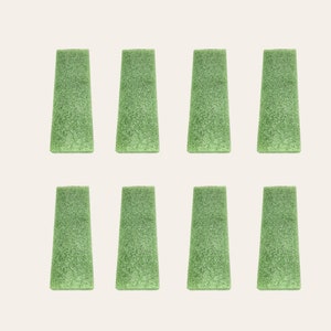 May include: Eight green foam blocks arranged in two rows of four. The blocks are rectangular with rounded edges and a textured surface.
