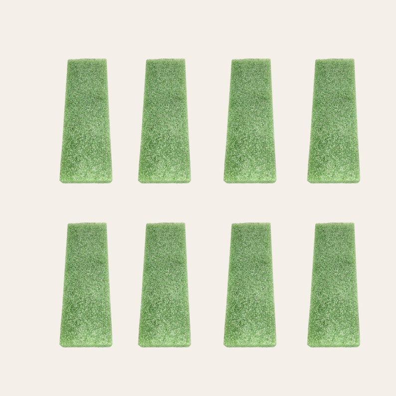 May include: Eight green foam blocks arranged in two rows of four. The blocks are rectangular with rounded edges and a textured surface.