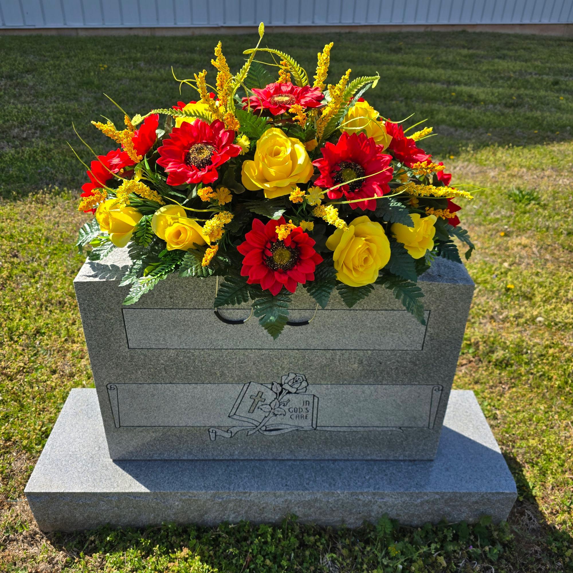 This headstone saddle includes Red Sunflowers and Yellow Elegant Roses.  It is a memorial decoration.