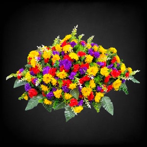 This Headstone Saddle has grave flowers including Multi-Colored Mini Mums. It is a perfect funeral or cemetery decoration.