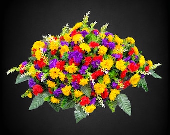 This Headstone Saddle has grave flowers including Multi-Colored Mini Mums. It is a perfect funeral or cemetery decoration.