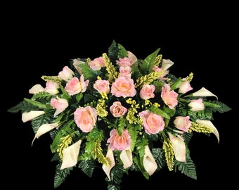 This Headstone Saddle has silk grave flowers including Cream Pink Calla Lilies and Roses. It is a perfect funeral or cemetery decoration.