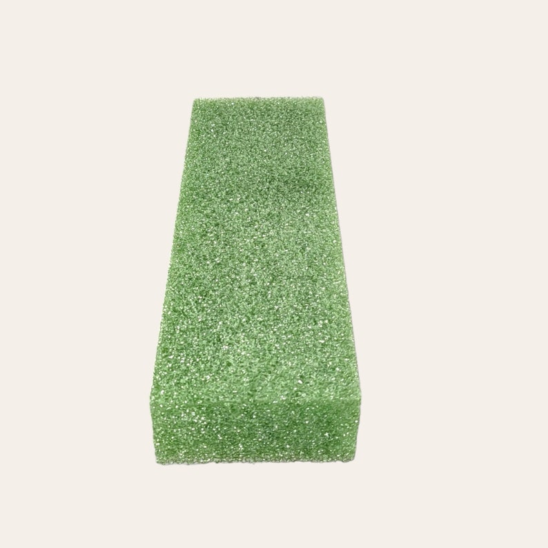 May include: A green rectangular block of floral foam, used for arranging flowers.