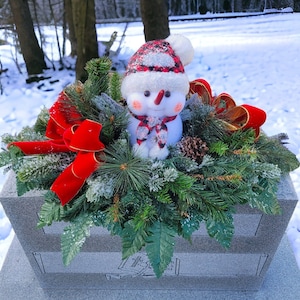 This Chubby Snowman  Christmas cemetery saddle has greenery and a red velvet bow. It is a winter memorial decoration.