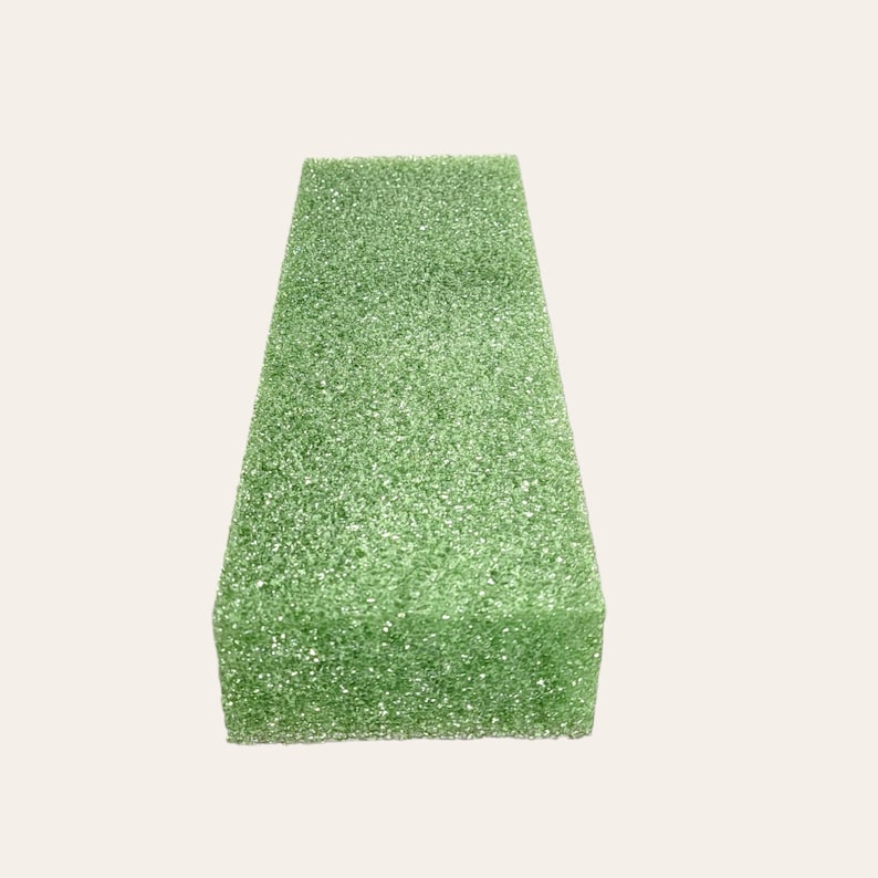 May include: A green rectangular block of floral foam, used for arranging flowers.