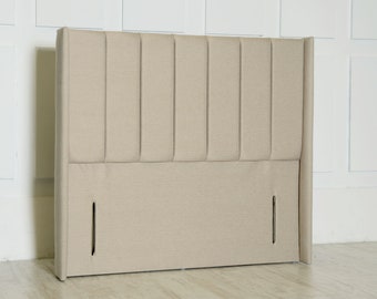 May include: A beige upholstered headboard with vertical channel tufting and a slightly curved top. The headboard has two small openings at the bottom.