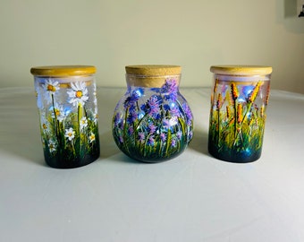 A set of three hand painted and fired glass containers with lids by Andrew Jenkins