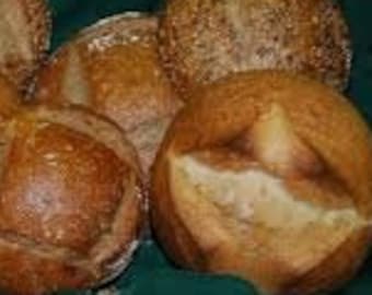 Può includere: Assortimento di pani appena sfornati, tra cui una pagnotta rotonda con una crosta ricoperta di semi, una pagnotta rotonda con una crosta dorata e una pagnotta con una crosta bianca.
