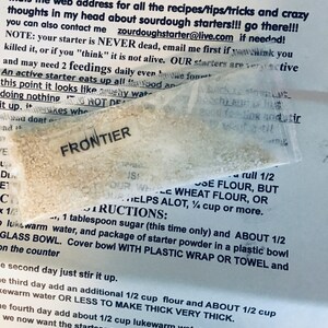 May include: A close-up of a white paper with instructions for making sourdough starter. The text includes the website address "https://www.zourdough.com/" and instructions for feeding the starter with 1/2 cup of whole wheat flour or 1/2 cup of all-purpose flour.