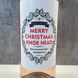 Puede incluir: Una botella de vino rosado con una etiqueta blanca que dice "Santapiss Merry Christmas Knob Head Best consumed when already pissed".