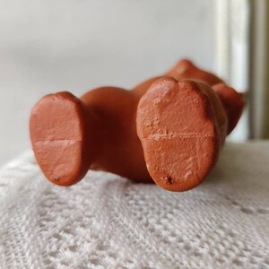 May include: Close-up of the bottom of a brown rubber toy. The toy has two feet and a flat bottom.