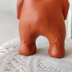 May include: A terracotta figurine of a bear with a triangular mark on the bottom of one foot and the number "30" on the other foot.