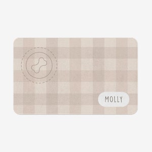 以下が含まれることがあります： 骨のアイコンと「MOLLY」という名前が印刷された、ベージュと白のチェック柄の犬用ベッドです。