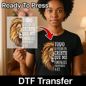 Puede incluir: Camiseta negra con un diseño de león dorado y el texto "TODO LO PUEDO EN CRISTO QUE ME FORTALECE FILIPENSES 4:13". La imagen también muestra una transferencia DTF con el mismo diseño y las palabras "Ready To Press".