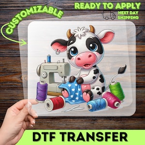 May include: DTF transfer featuring a cartoon cow sewing with a sewing machine. The cow is black and white with blue eyes and a pink nose. Spools of thread in various colors are scattered around the sewing machine. The text "CUSTOMIZABLE" and "READY TO APPLY" are visible.