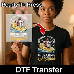 May include: Black t-shirt with a graphic of Jesus sitting on a lemon, with the text "Life Gave Me Some Lemons But My Jesus He Be Making Lemonade." The words "Ready To Press" and "DTF Transfer" are also visible.