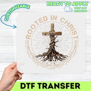 May include: A white DTF transfer featuring a wooden cross with roots and the text "ROOTED IN CHRIST". The design includes a circular element with text and a crown of thorns. The words "CUSTOMIZABLE" and "READY TO APPLY" are also visible.
