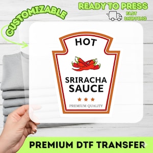 Könnte beinhalten: Ein weißer quadratischer DTF-Transfer mit einem Ketchupflaschen-Design mit den Wörtern "HOT" und "SRIRACHA SAUCE" in Schwarz. Das Design enthält rote Chilischoten und den Text "PREMIUM QUALITY". Der Transfer ist mit "CUSTOMIZABLE" und "READY TO PRESS" beschriftet.