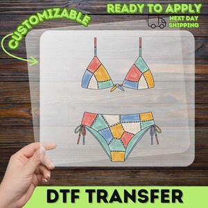 May include: A clear DTF transfer sheet featuring a colorful bikini illustration with a patchwork design. The bikini top has triangle cups and the bikini bottom features side ties, both decorated with a multi-colored grid pattern of blue, yellow, green, and red segments with black stitched outlines.
