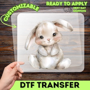 May include: A DTF transfer featuring a watercolor illustration of a cute, seated bunny with large eyes and pink cheeks. The transfer is customizable and ready to apply. The image includes the text "READY TO APPLY" and "NEXT DAY SHIPPING".