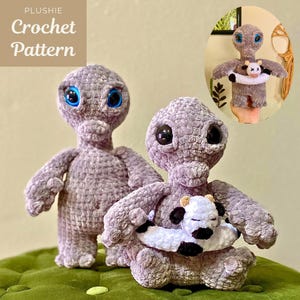 May include: Two grey alien plush dolls with large black and blue eyes. One doll holds a plush cow. The dolls are on a green surface. The text "PLUSHIE Crochet Pattern" is in the upper left corner.