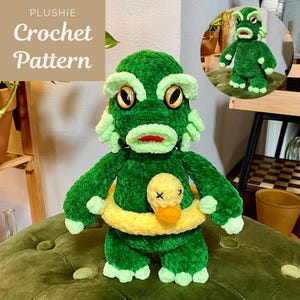 Puede incluir: Un peluche verde con forma de criatura con grandes ojos amarillos, boca roja y un salvavidas amarillo que sostiene un pato amarillo. El texto "PLUSHIE Crochet Pattern" está presente.