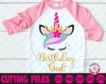 May include: A white t-shirt with a pink and white unicorn design and the text "Birthday Girl" in gold glitter. The unicorn has a gold crown, pink and purple mane, and closed eyes.