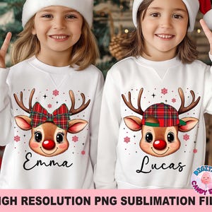 May include: Two white sweatshirts with reindeer graphics. One reindeer has a red plaid bow, the other a plaid cap. The names "Emma" and "Lucas" are below the reindeer faces. Red snowflakes and stars are also on the shirts.