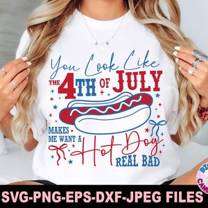 May include: White t-shirt with a patriotic design featuring the text "You Look Like the 4th of July" and a hot dog illustration. The design is in red, white, and blue, with stars and decorative elements.