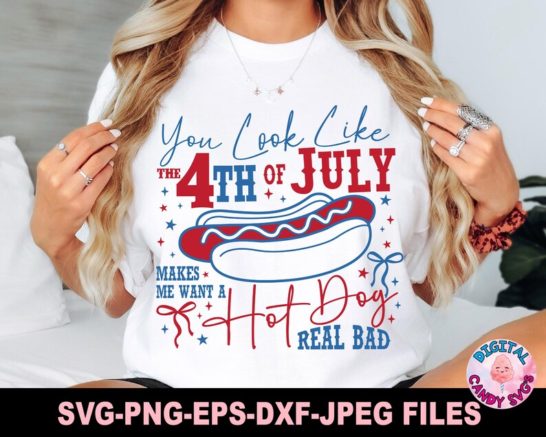 May include: White t-shirt with a patriotic design featuring the text "You Look Like the 4th of July" and a hot dog illustration. The design is in red, white, and blue, with stars and decorative elements.