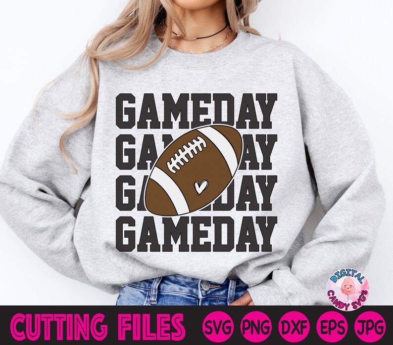 May include: A grey sweatshirt with the text "GAMEDAY" repeated four times, with a brown and white football graphic in the centre. The football has a small heart on it.