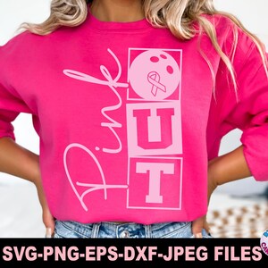 May include: A bright pink long-sleeve sweatshirt featuring a graphic design with the word Pink in cursive script and the letters OUT stacked in blocks. The letter O contains a bowling ball with a pink ribbon symbol inside the circular design.