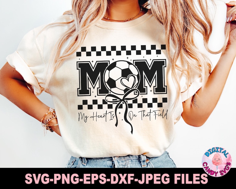 May include: A white t-shirt with a black and white checkered design. The shirt features a black and white soccer ball with a heart and the text "MOM" in a black and white varsity font. The text "My Heart Is On That Field" is printed below the soccer ball.