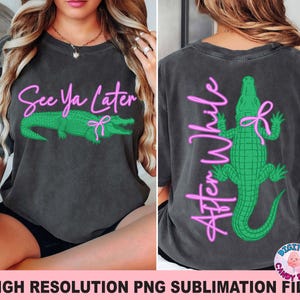 May include: Dark gray t-shirt with a green alligator design and the text "See Ya Later" in pink on the front. The back of the shirt features a green alligator and the text "After While" in pink.