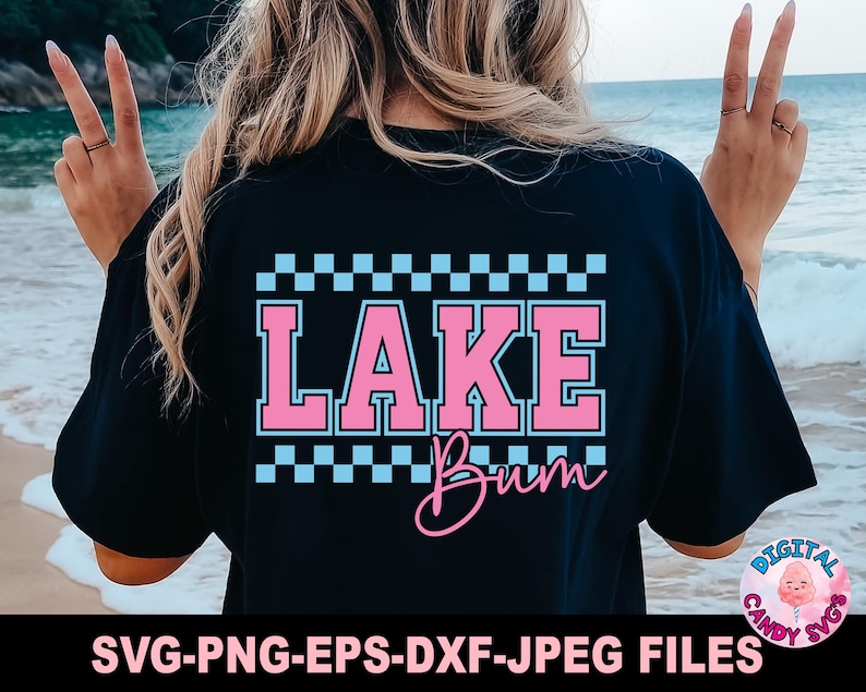 May include: Black t-shirt with the words "LAKE Bum" in pink and white, with a checkered pattern above. The shirt also has the text "SVG-PNG-EPS-DXF-JPEG FILES" at the bottom. The shirt is a casual style.