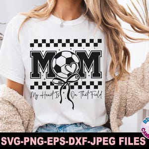 May include: White t-shirt with a black and white checkered design. The text "MOM" is in black with a white soccer ball and heart graphic. The text "My Heart Is On That Field" is below the graphic.